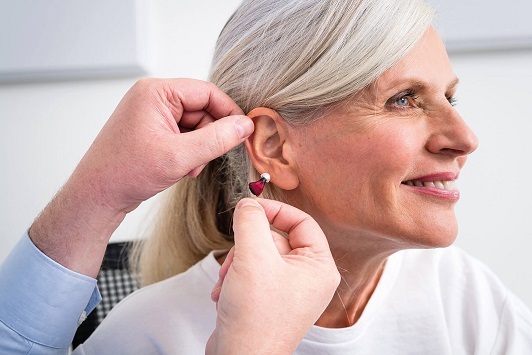 Ältere Frau bekommt ein Hörgerät eingesetzt, Hörakustiker berät zur Hörhilfe.